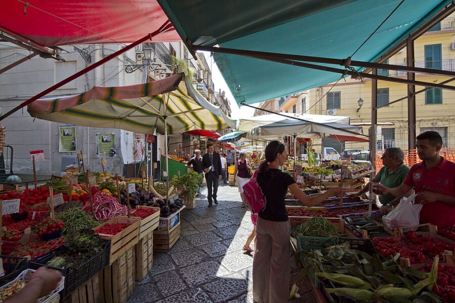 Market vendors and market shopper on the historic old streets of Palermo in Sicily