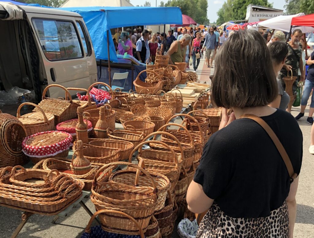 Woman standing in front on wicker baskets at a market