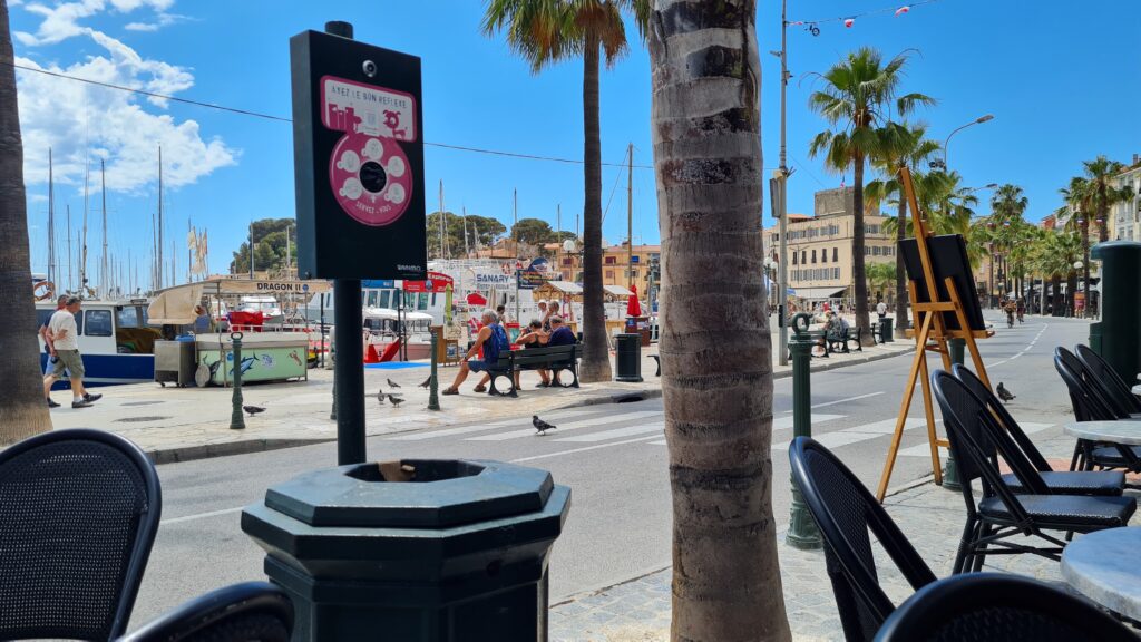 A city street with palm trees and people walking