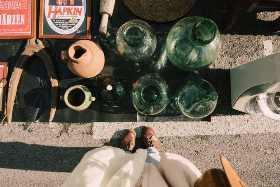 female feet next to the transparent green old jars at a flea market