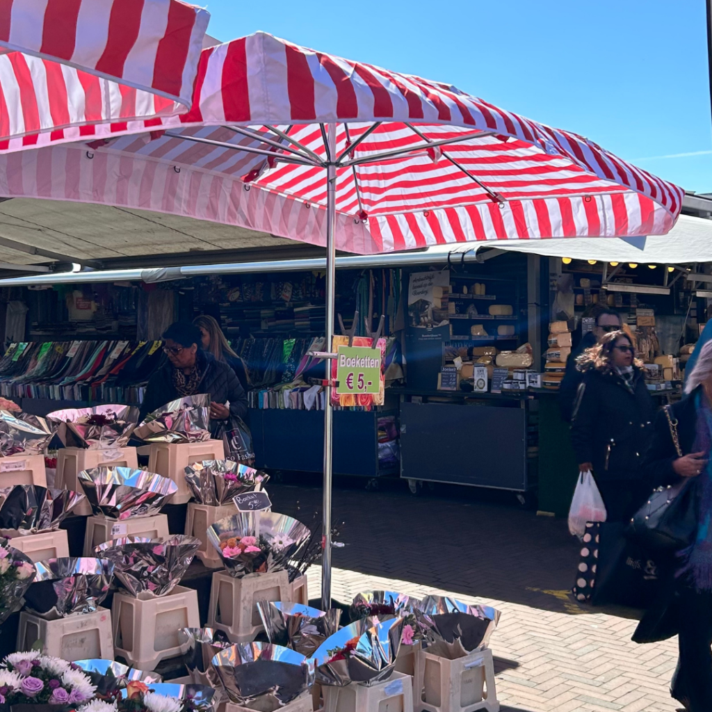 red striped sun umbrella with flowers underneath atthe hague market