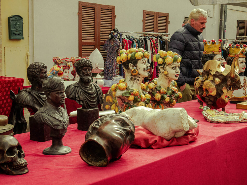 at the market in Civitanova Marche Colorful head shaped vases on a table with red table cloth